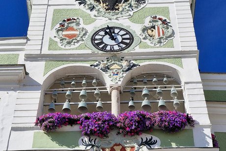 Mittlerer Rathausturm Bad Ischl. Dar&uuml;ber Uhr und zwei Wappen. Oben der Doppeladler