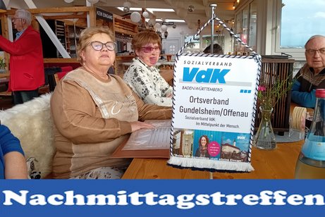 Bild zeigt Personen beim Sonnenschein beim Nachmittagstreffen am Tisch essen und trinken