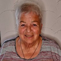 Elfriede Stare l&auml;chelnd in gestreiftem Oberteil, vor einer wei&szlig;en Wand.