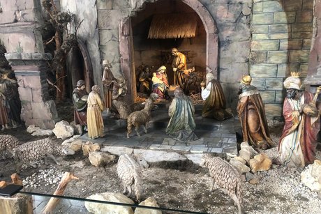 Detailreiche Weihnachtskrippe mit Maria, die das Jesuskind im Arm h&auml;lt, Josef an ihrer Seite sowie realistisch gestalteten Figuren der Hirten und zwei der drei Heiligen K&ouml;nige vor dem Stall.