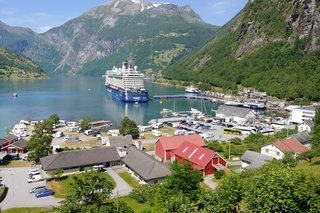 Fjord in Norwegen, mit Kreuzfahrtschiff und Häuser im Vordergrund