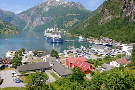 Fjord in Norwegen, mit Kreuzfahrtschiff und Häuser im Vordergrund