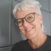 Eine Frau mit Brille und grauen Haaren und freundlichem L&auml;cheln