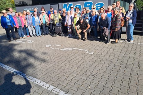 Die 40 Reisenden stehen bei sommerlichen Wetter vor dem Reisebus