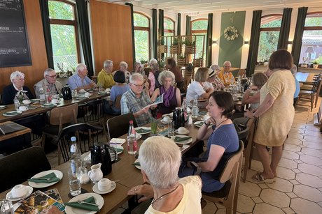 Besucherinnen und Besucher des Sommerfests sitzen an Tischen im Restaurant Hasenheim