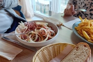 Bild zeigt einen Teller mit Wurstsalat mit Brot auf dem Tisch