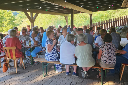 Mitglieder und Freunde des VdK Ortsverbandes sitzen in geselliger Runde auf der Au&szlig;enterrasse an der Fischerh&uuml;tte am Mondsee.
