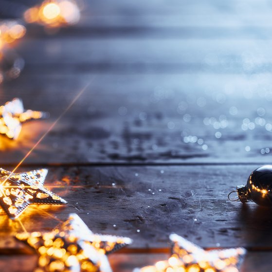 Weihnachtsdekoration mit leuchtenden Lichtern in Sternenform, die auf einem Holztisch liegen.
