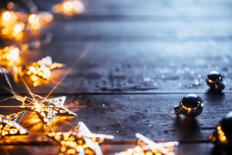 Weihnachtsdekoration mit leuchtenden Lichtern in Sternenform, die auf einem Holztisch liegen.