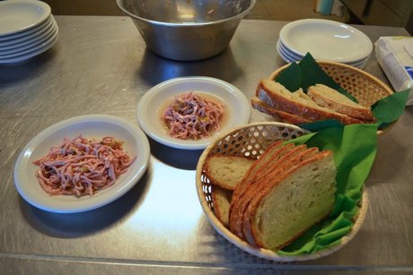 Zwei Teller mit Wurstsalat, daneben ein Korb mit Brotscheiben.