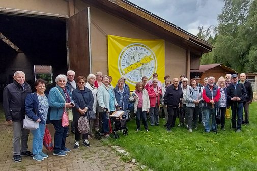 Sommerausflug VdK OV RSKN-Esslingen 2025 Ältere Menschen vor einer Scheune mit einem Plakat der Hohensteiner Hofkäserei Albkäs