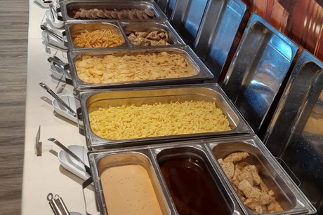 Warmes Buffet aus einer anderen Perspektive mit Gem&uuml;se und So&szlig;en im Vordergrund, Sp&auml;tzle und Kartoffelgratin