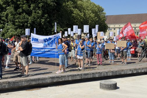 Demonstrationszug: Menschen mit Banner und Plakaten laufen durch die Innenstadt von Karlsruhe, die Sonne scheint.