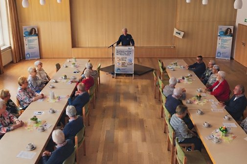 Polizeibeamter am Rednerpult. Links und rechts davon Roll up Ortsverein Untergruppenbach. Vordergrund zwei Tischreihen mit zh&ouml;renden.