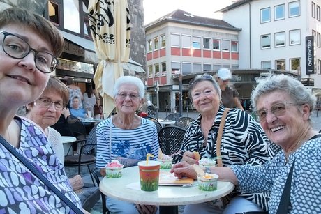 ESTiVAL Fünf Damen sitzen an einem Bistrotisch, auf dem kleine Papp-Eisbecher stehen, und lächeln in die Kamera.