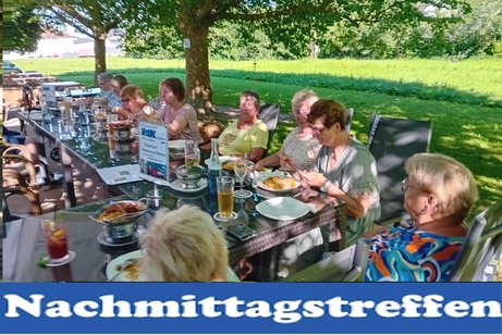 Bild zeig Leute an den Tischen im Freien sitzend und trinken