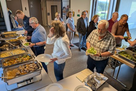 Mitglieder stehen am Essens-Buffet an