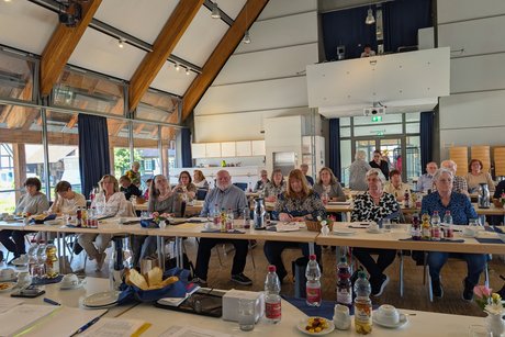 Blick von vorne auf die linke Seite der vordersten Tischreihe, in der die Vertreter der Ortsverb&auml;nde dem Vortrag aufmerksam folgen.