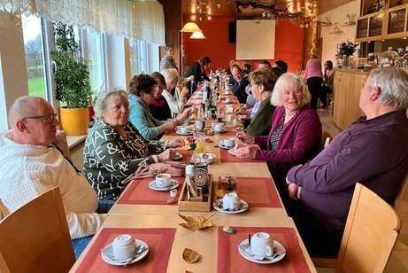 Mehrere Personen sitzen um eine gedeckte Kaffeetafel