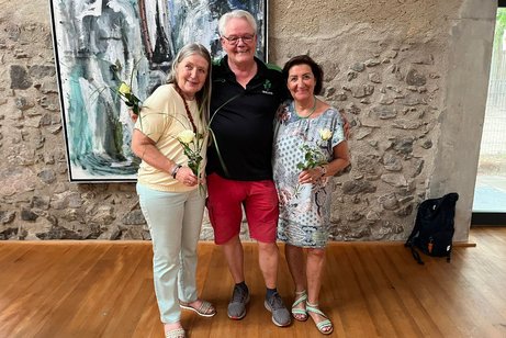 Die drei Mitglieder des gesch&auml;ftsf&uuml;hrenden Vorstands vor dem Gem&auml;lde im B&uuml;rgersaal stehend, von rechts: Ortsvorsitzende Brigitte Mauz, Schatzmeister Andreas Miller, Frauenbeauftragte und Schriftf&uuml;hrerin Helga Imhof