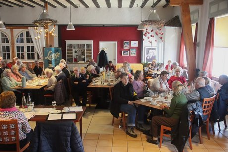 Mitglieder sitzen an Tischen beim Kaffee trinken und Kuchen essen