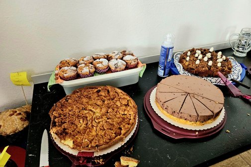 Ein Fotoausschnitt vom Kuchenbuffet. Ein Apfelkuchen, eine Schokoladensahne und Muffins sind zu sehen.