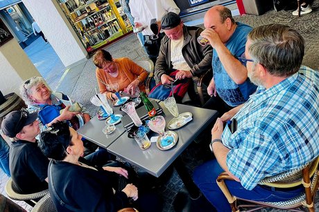Um einen Tisch in einem Eiscafe sitzen wir zu acht vor den leer gegessenen Eisbecher.