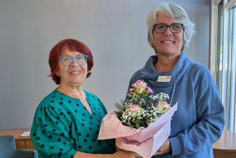 Frau Baur &uuml;berreicht Frau Pohnert einen Blumenstrau&szlig;.
