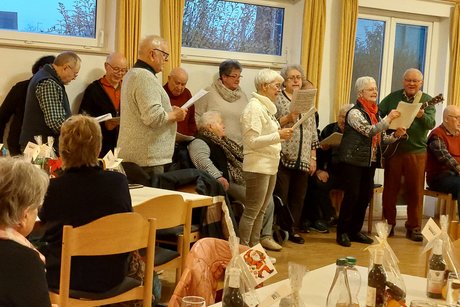 Männer und Frauen stehen in einer Halle und singen.