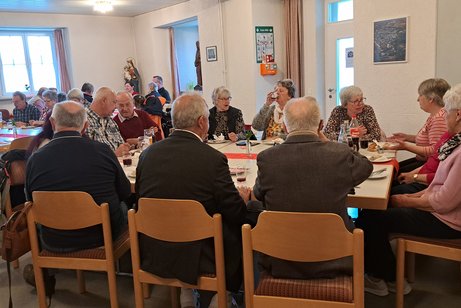 Teilnehmer beim Weißwurstfrühstück, an Tischen sitzend