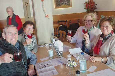 Besen Neipperg Drei ältere Frauen und ein älterer Herr sitzen an einem Tisch, auf dem Speisekarten liegen, und lächeln in die Kamera.