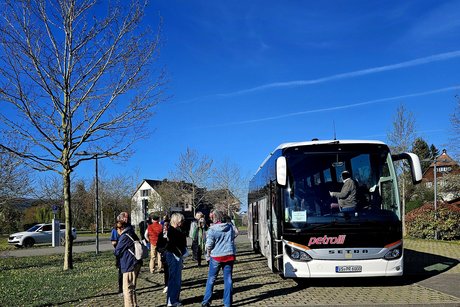 Der Reisebus und ein paar Fahrg&auml;ste daneben, der Himmel ist strahlend blau.