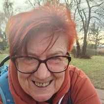 Eine Frohnatur von Mensch. Eine rothaarige lachende Frau mit einer gro&szlig;en rotbrauen Kunstoffbrille mit runden Gl&auml;sern. Sie hat, wenn sie lacht an beiden Mundwickeln Gr&uuml;bchen.
