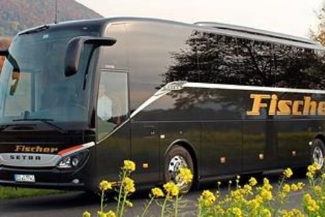 Fahrender Reisebus auf Stra&szlig;e in bl&uuml;hender Landschaft