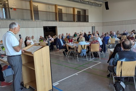 Der Kreisverbandsvorsitzende Manfred Merstetter am Rednerpult begrüßt die an Tischen sitzenden Mitglieder,
