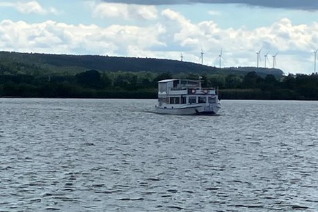 Blick vom Bootssteg auf den See, ein Schiff f&auml;hrt in Richtung des Stegs.