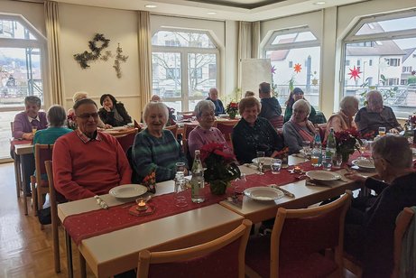 Panoramafoto des Festsaals mit mehreren Tischen, an denen vorwiegend &auml;ltere Menschen sitzen und sich angeregt unterhalten