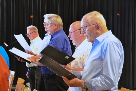 Fünf Männer mit Chormappen in den Händen, die singen.