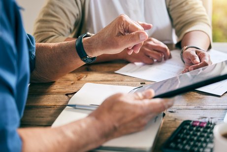 Beratungsgespr&auml;ch, zwei Menschen sitzen an einem Tisch, es sind Papiere und H&auml;nde zu sehen.