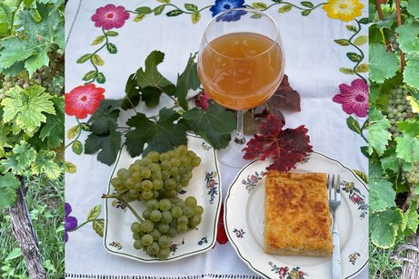 Gedeck mit Weintrauben, Teller mit Zwiebelkuche und Weinglas mit neuem Wein