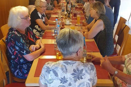 Mehrere Personen sitzen um eine gedeckte Kaffeetafel