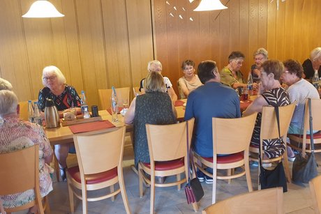 Mehrere Personen sitzen um eine gedeckte Kaffeetafel