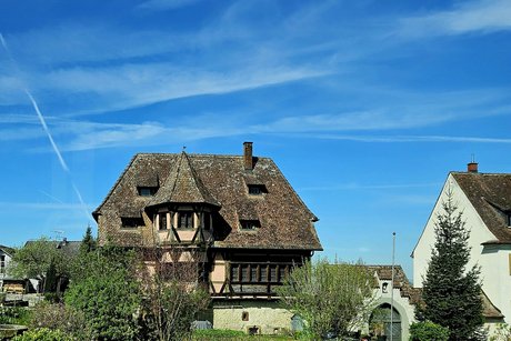 Ein wundersch&ouml;nes altes Geb&auml;ude mit einem kleinen T&uuml;rmchen steht im Gr&uuml;nen.