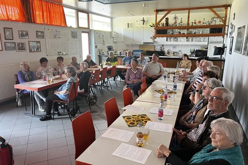 Viele &auml;ltere Leute sitzen um Tische