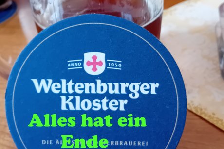 Bild zeigt einen Bierkrug an dem ein blauer Bierdeckel mit den Ausspruch " Alles hat ein Ende nur die Wurst hat Zwei
