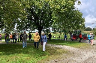 Mostbauer-Zügle mit angehängten Wagen und mehreren, aussteigenden Fahrgästen