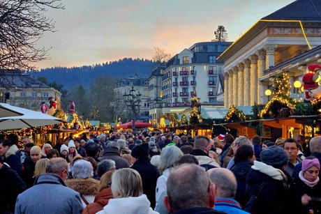 Weihnachtsmarkt - rechts und links sch&ouml;n beleuchtete und weihnachtlich geschm&uuml;ckte St&auml;nde , in der Mitte Massen von Leuten bis zu 12 nebeneinander spazieren dicht gedr&auml;ngt durch den Markt.