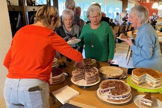 Mehrere Personen stehen um ein Kuchenbuffet