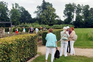 Eine Frauengruppe, die miteinander redet, im Landschaftspark mit in Form geschnittenen Hecken.