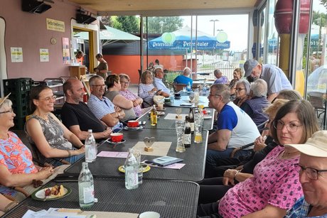 mehrere Menschen sitzen an Tischen im Minigolf